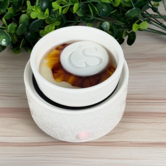 White electric wax warmer melting an Ambered Bourbon wax tart, topped with a GS logo wax embed.