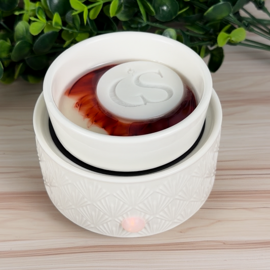Apple & Spice wax melt tart melting in a white electric wax warmer, GS logo disc floating on melted wax.