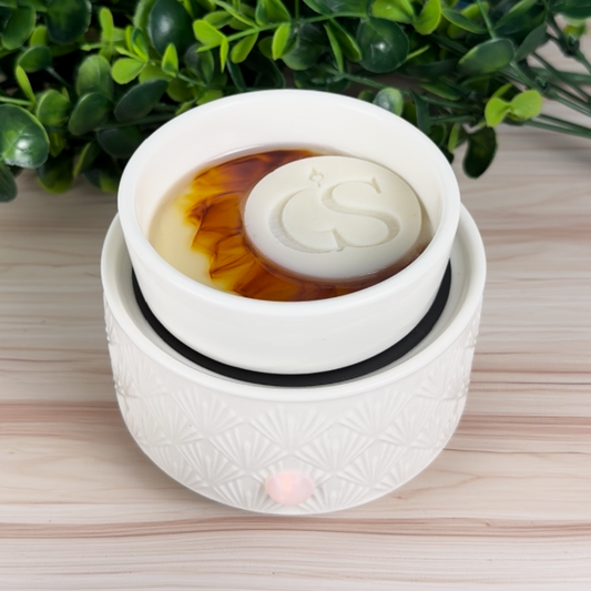 Cinnamon Roll color-reveal wax melt warming in a white electric wax warmer with GS logo puck on top