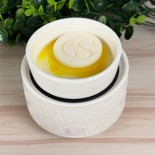 Lemon Glow-Up wax melt tart melting in a white electric wax warmer, showing bright yellow color-reveal wax swirl.