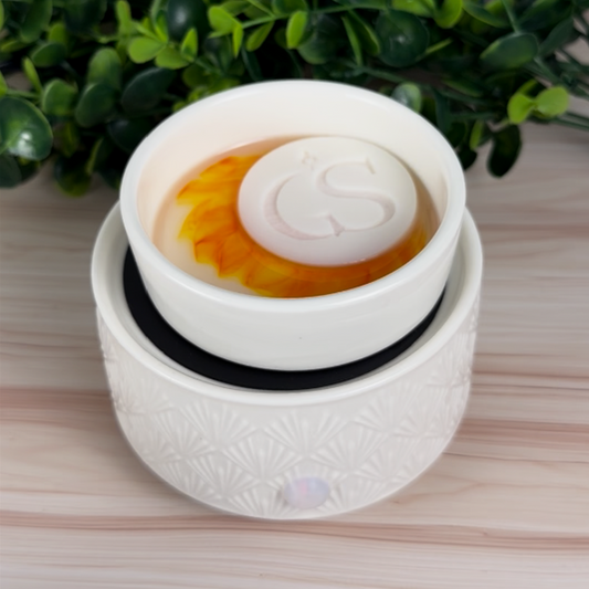 My Cereal Era color-reveal wax melt tart warming in a white electric wax warmer, showing orange melt swirl with GS wax puck on top.