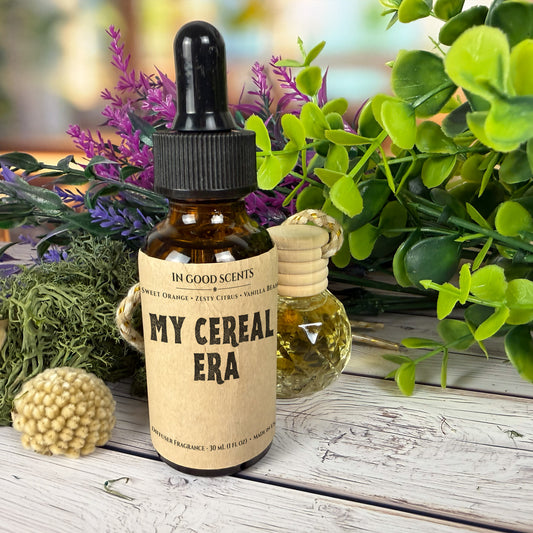 A bottle of 'My Cereal Era' fragrance with a dropper on a wooden surface surrounded by plants.