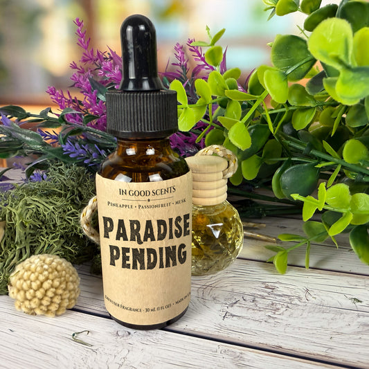 Bottle labeled 'Paradise Pending' with a dropper on a wooden surface with plants in the background