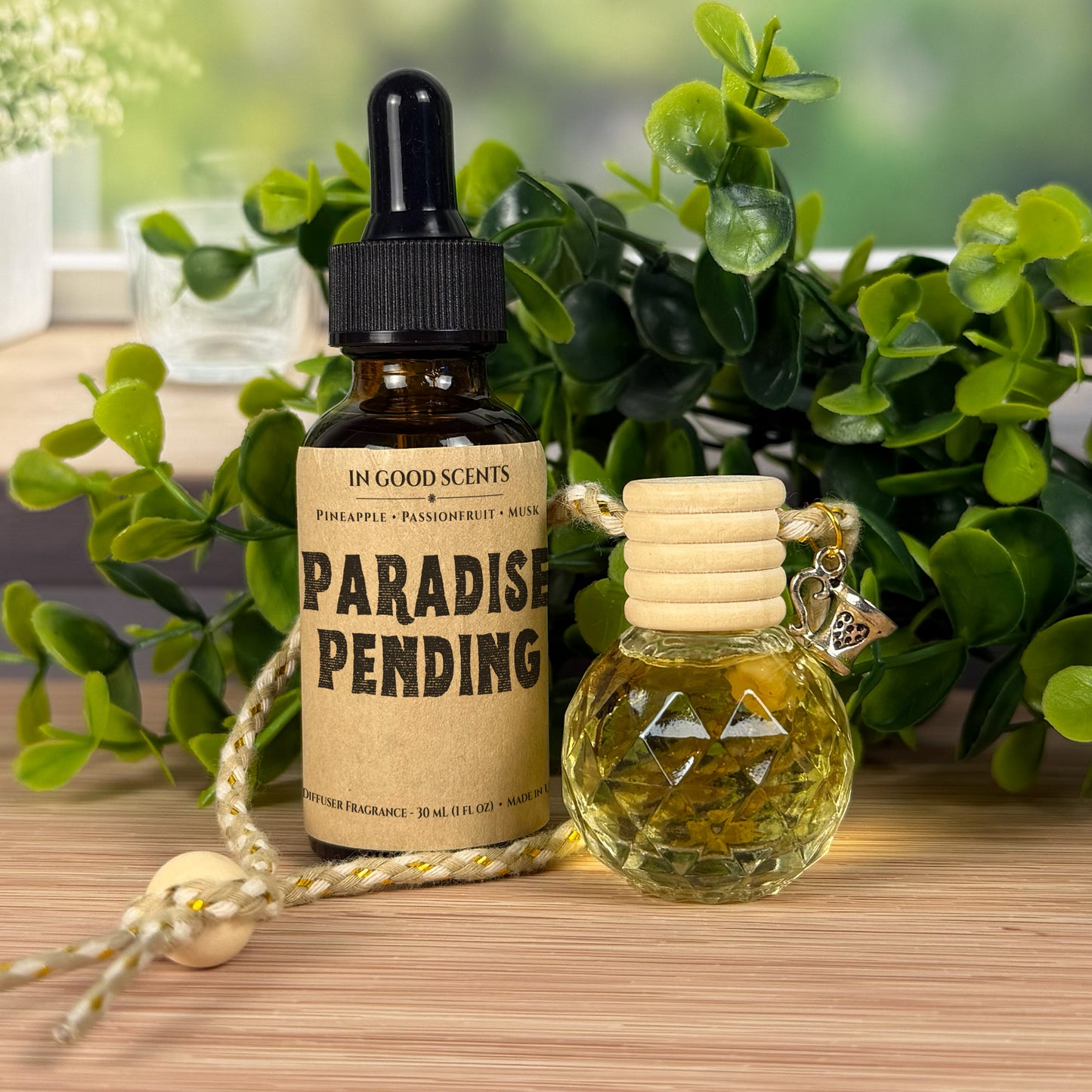 Two small bottles with labels on a wooden surface with greenery in the background