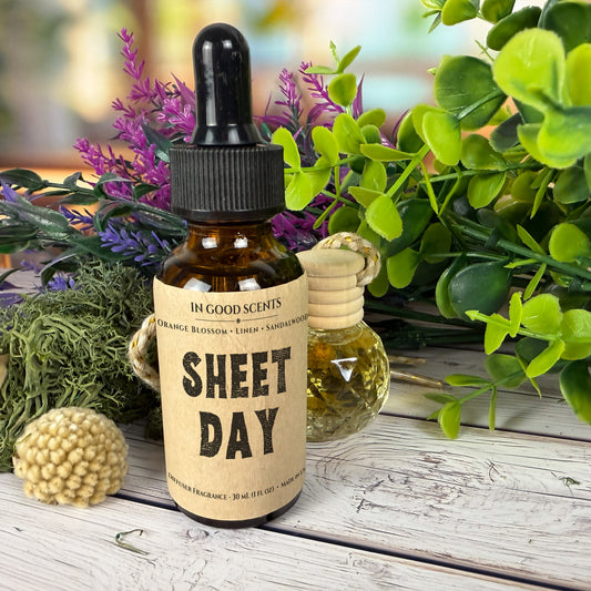 A bottle labeled 'Sheet Day' with a dropper on a wooden surface surrounded by plants.