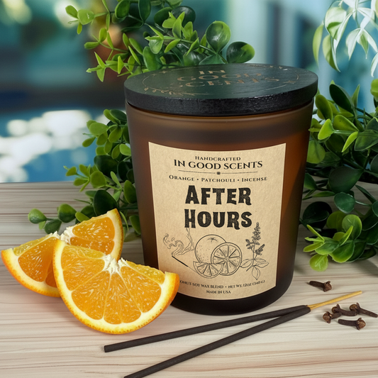 After Hours 12oz candle with lid in amber jar on wood surface with fresh orange slices, incense sticks, and greenery.