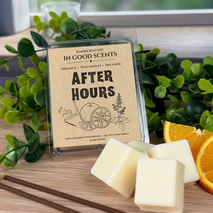 Wax melts in a container with 'In Good Scents' packaging on a wooden surface with greenery and oranges.