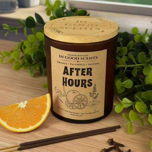 After Hours 8oz candle with bamboo lid — amber jar on a wooden table by a window with green leaves, orange slice, incense sticks, and cloves.