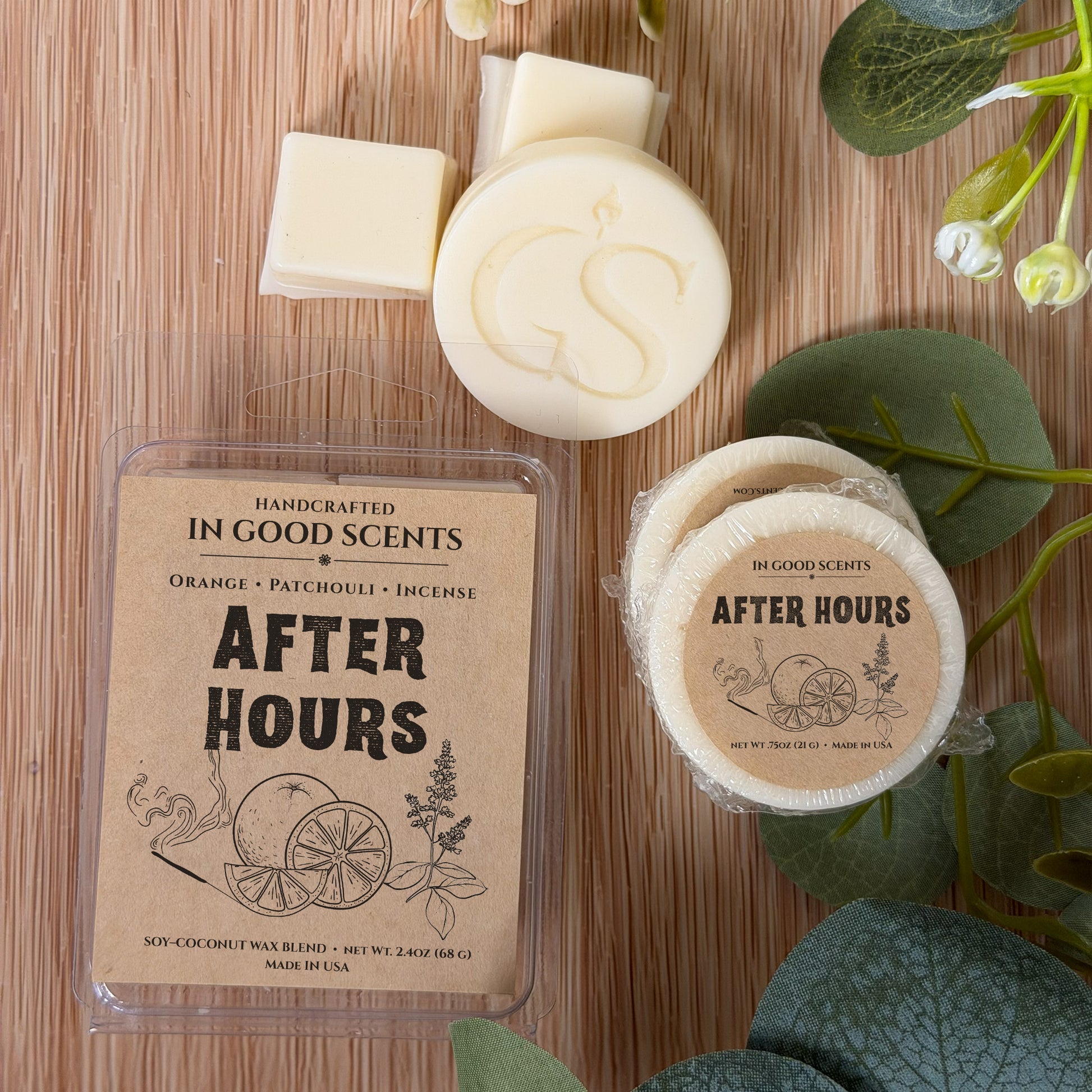 Handcrafted wax melts and packaging on a wooden surface with greenery.
