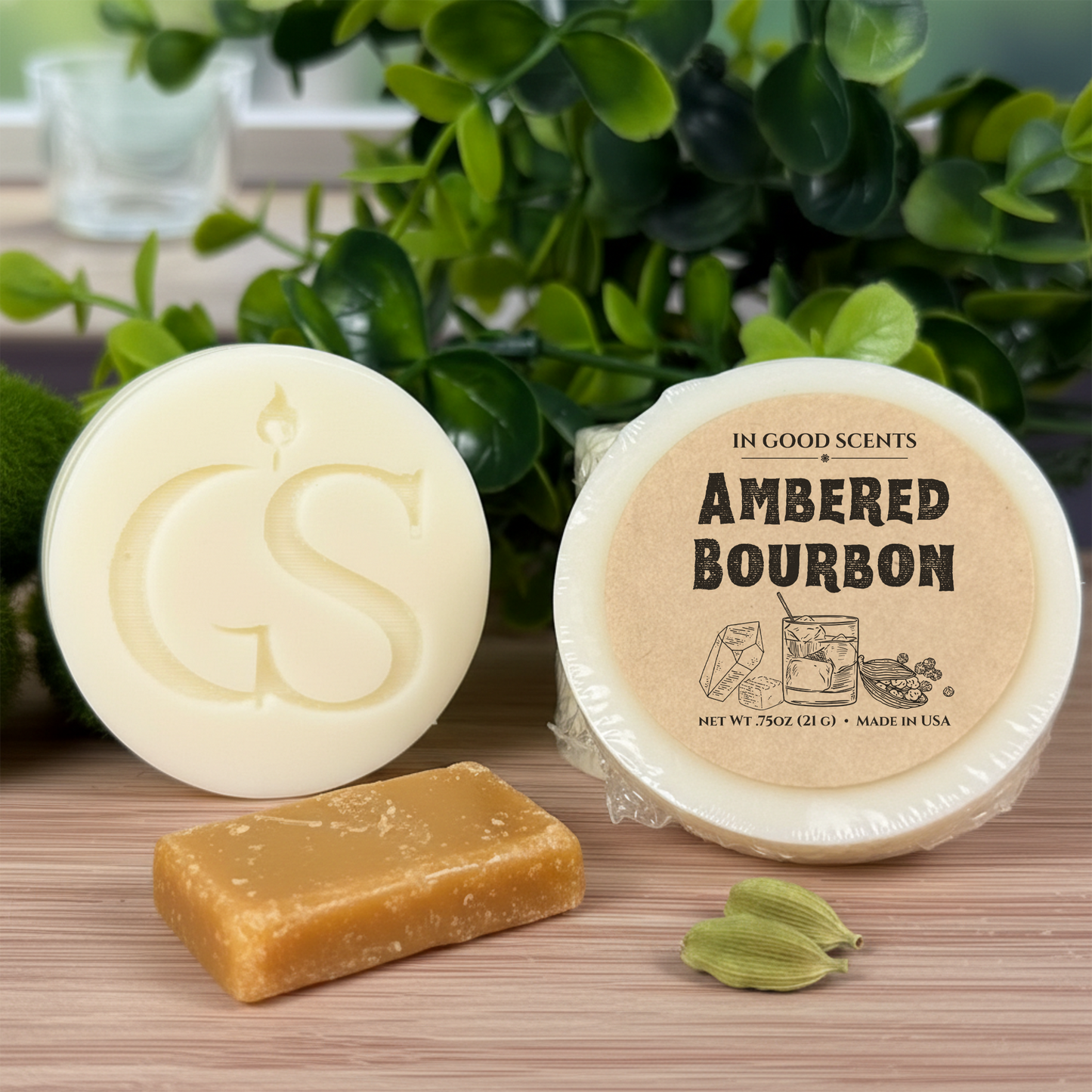 Ambered Bourbon wax melt tart (.75 oz) by In Good Scents, wrapped and labeled, shown beside GS logo melt with caramel candy and cardamom pods.