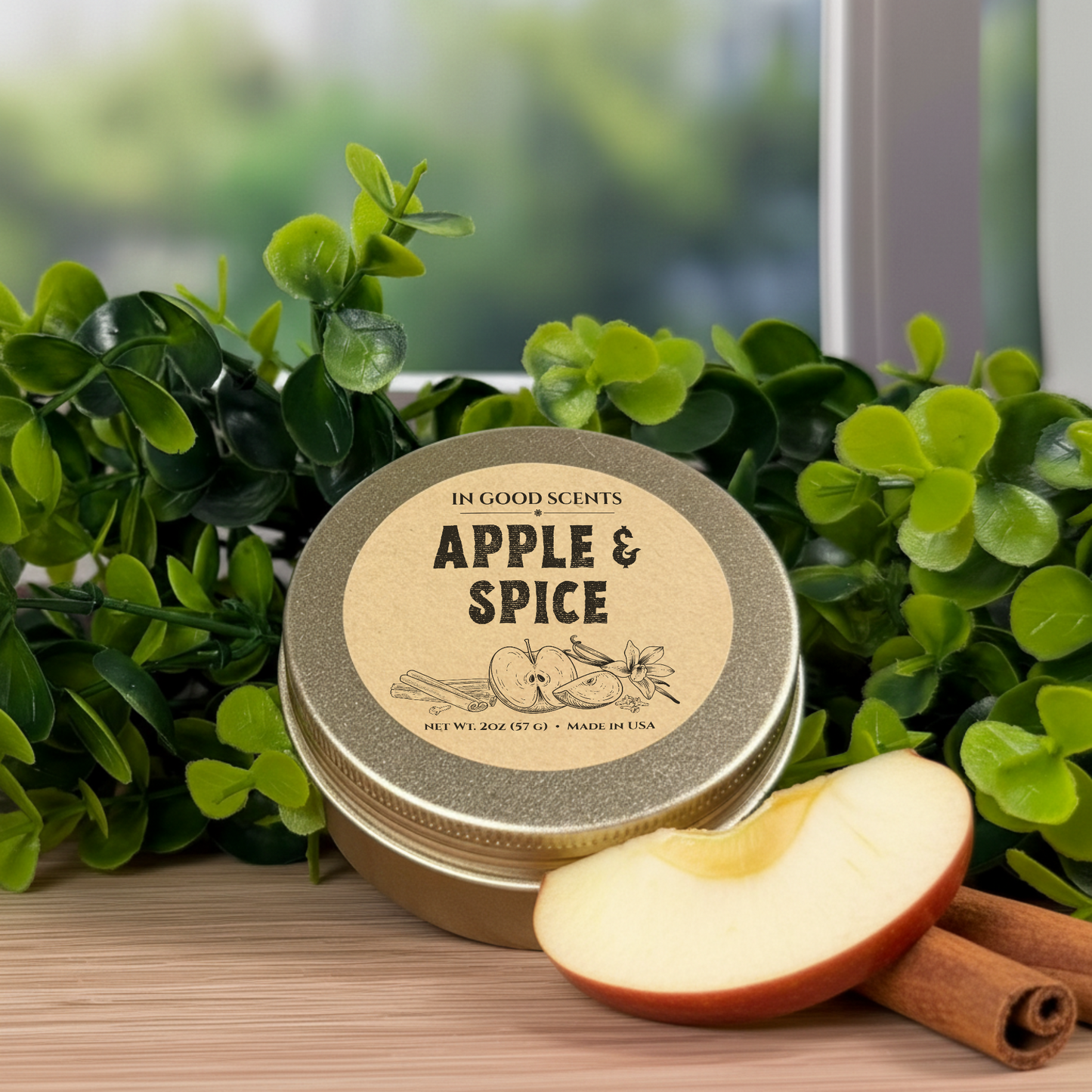 Apple & Spice 2oz candle tin with kraft lid label, styled with greenery, apple slice, and cinnamon stick.