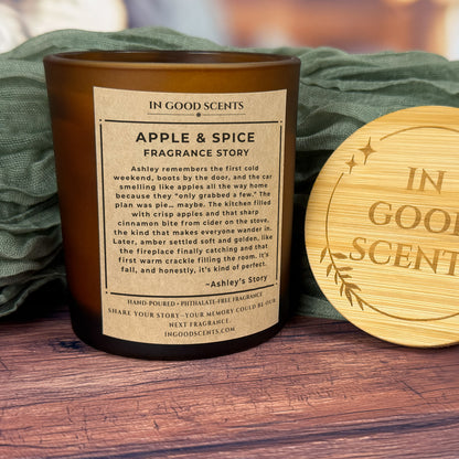 Back “Fragrance Story” label on Apple & Spice 8oz candle with bamboo lid next to the jar on a cozy fabric backdrop.