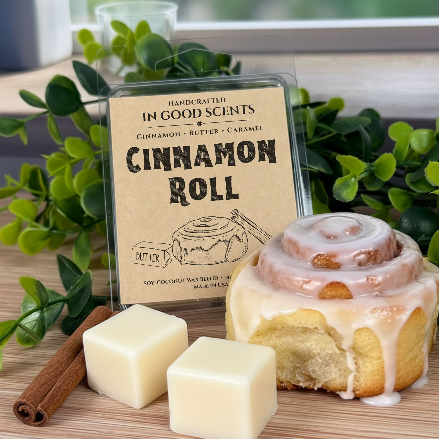 Cinnamon roll-themed wax melt with packaging labeled 'Cinnamon Roll' on a wooden surface with greenery.