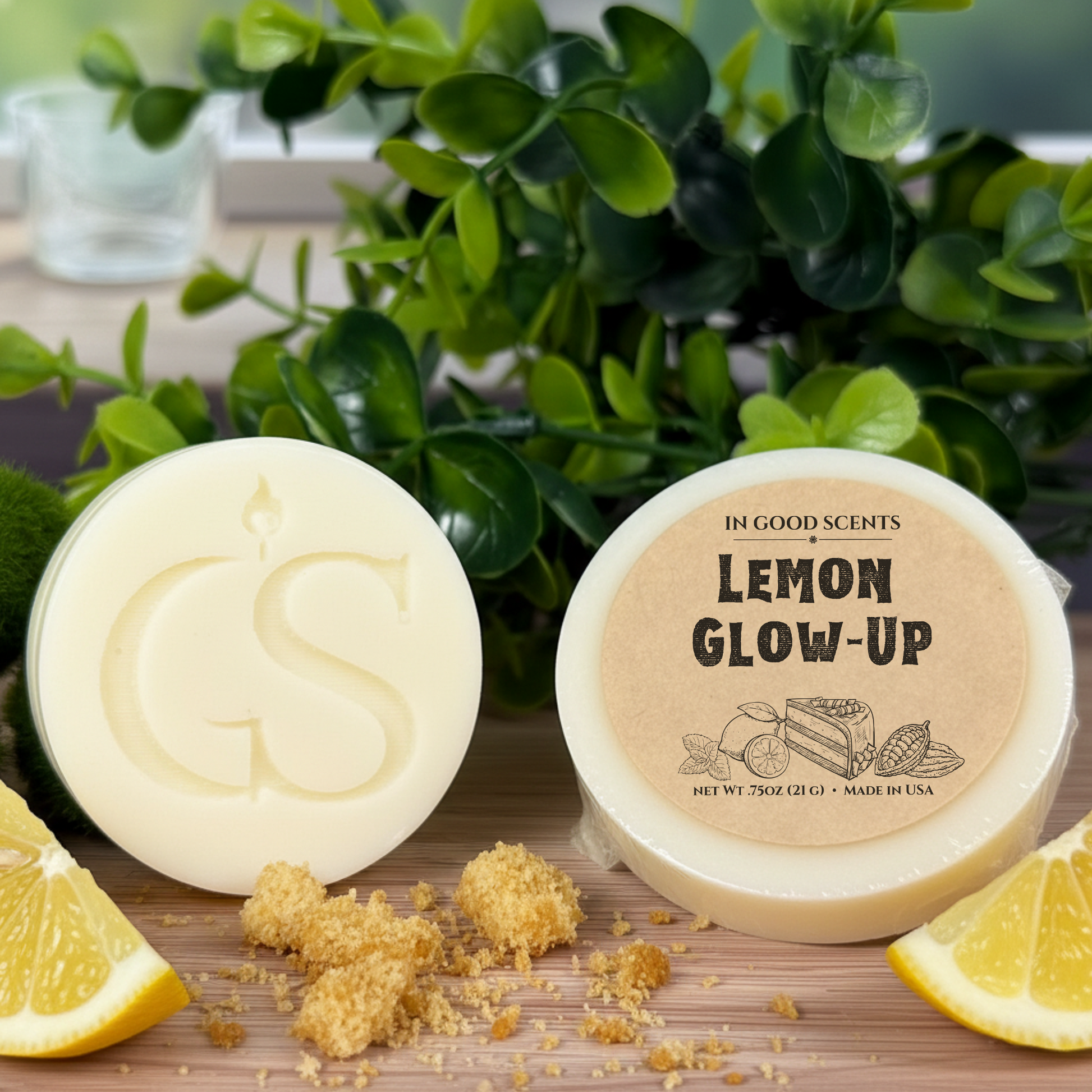 In Good Scents Lemon Glow-Up 0.75oz wax melt tart with GS logo tart beside labeled tart, styled with lemon slices on a wooden surface.