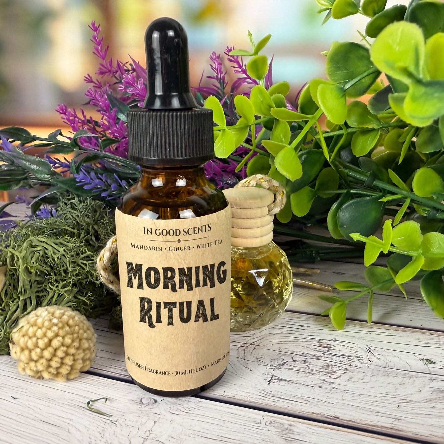 Bottle of 'Morning Ritual' fragrance with a dropper and label, surrounded by plants on a wooden surface.