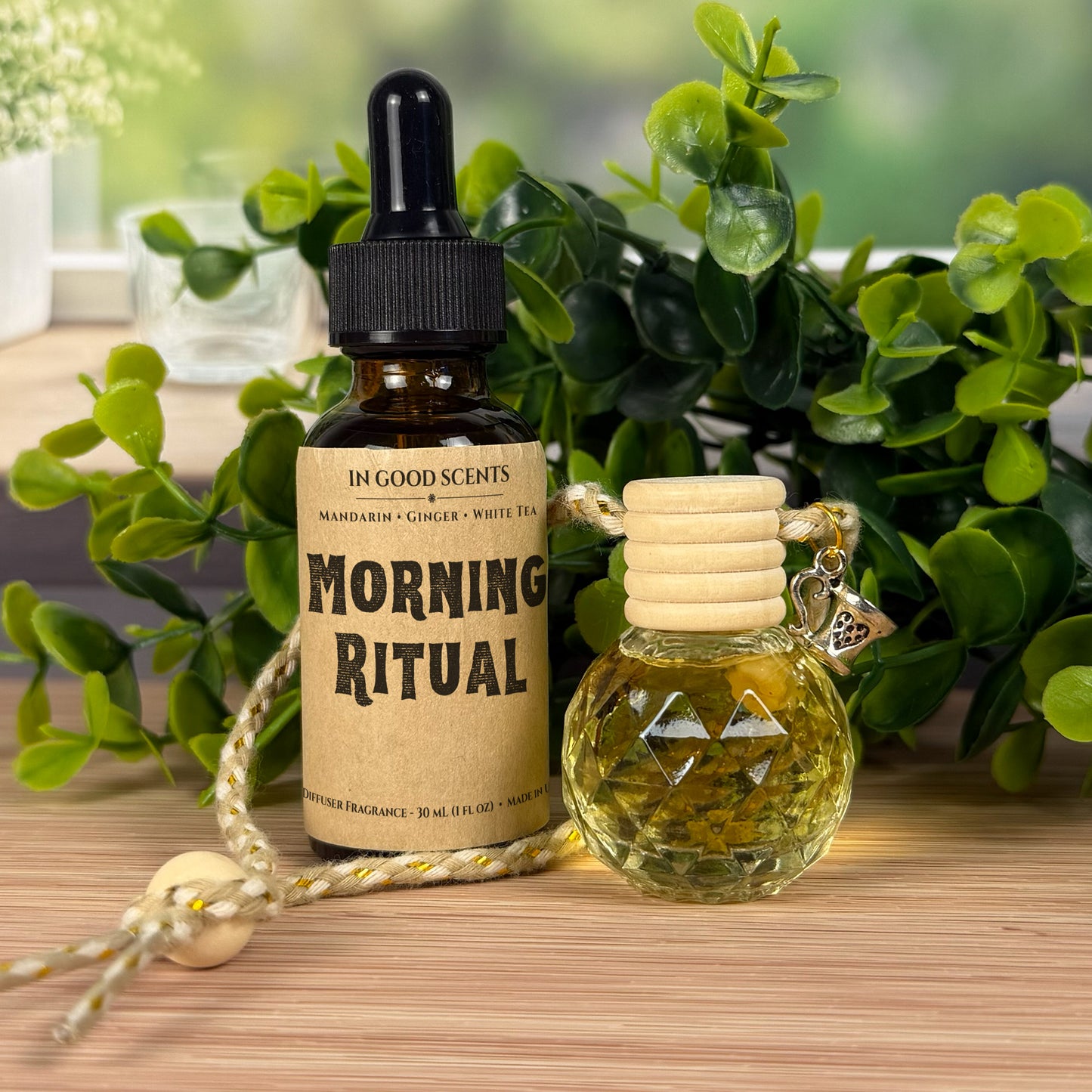 Two bottles of 'Morning Ritual' fragrance with a wooden cap on a wooden surface with greenery in the background.
