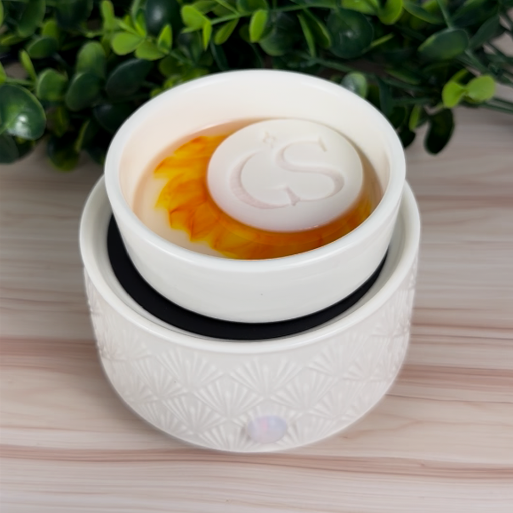 My Cereal Era color-reveal wax melt tart warming in a white electric wax warmer, showing orange melt swirl with GS wax puck on top.