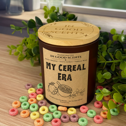 In Good Scents “My Cereal Era” 8oz amber jar candle with bamboo lid, styled with colorful cereal loops on a wood surface.