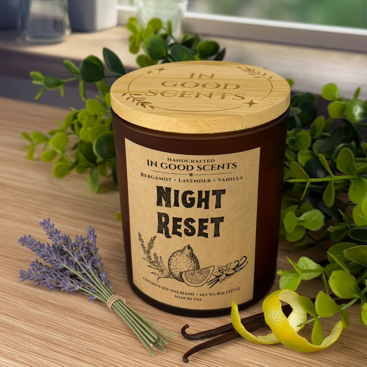 Night Reset 8oz candle with bamboo lid on a wooden counter, styled with lavender, vanilla beans, and citrus peel (In Good Scents).