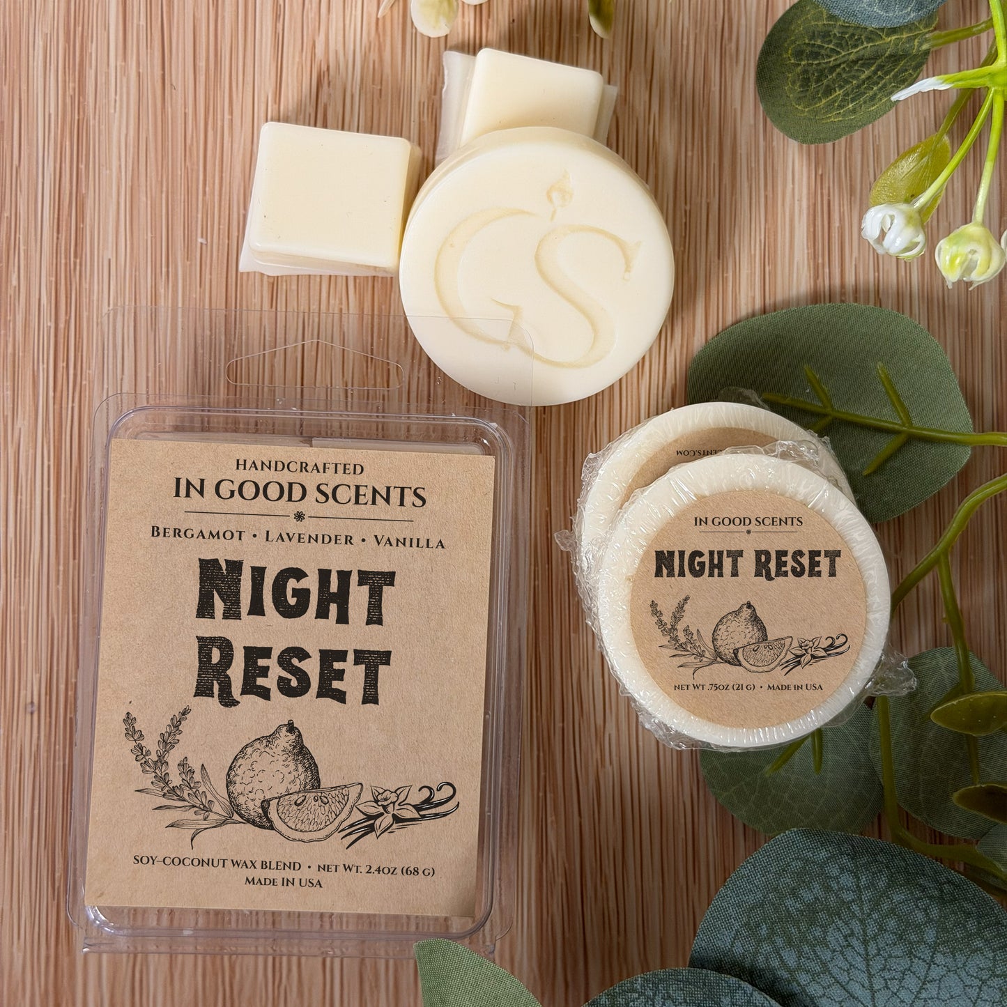 Handcrafted wax melt packaging on a wooden surface with greenery.