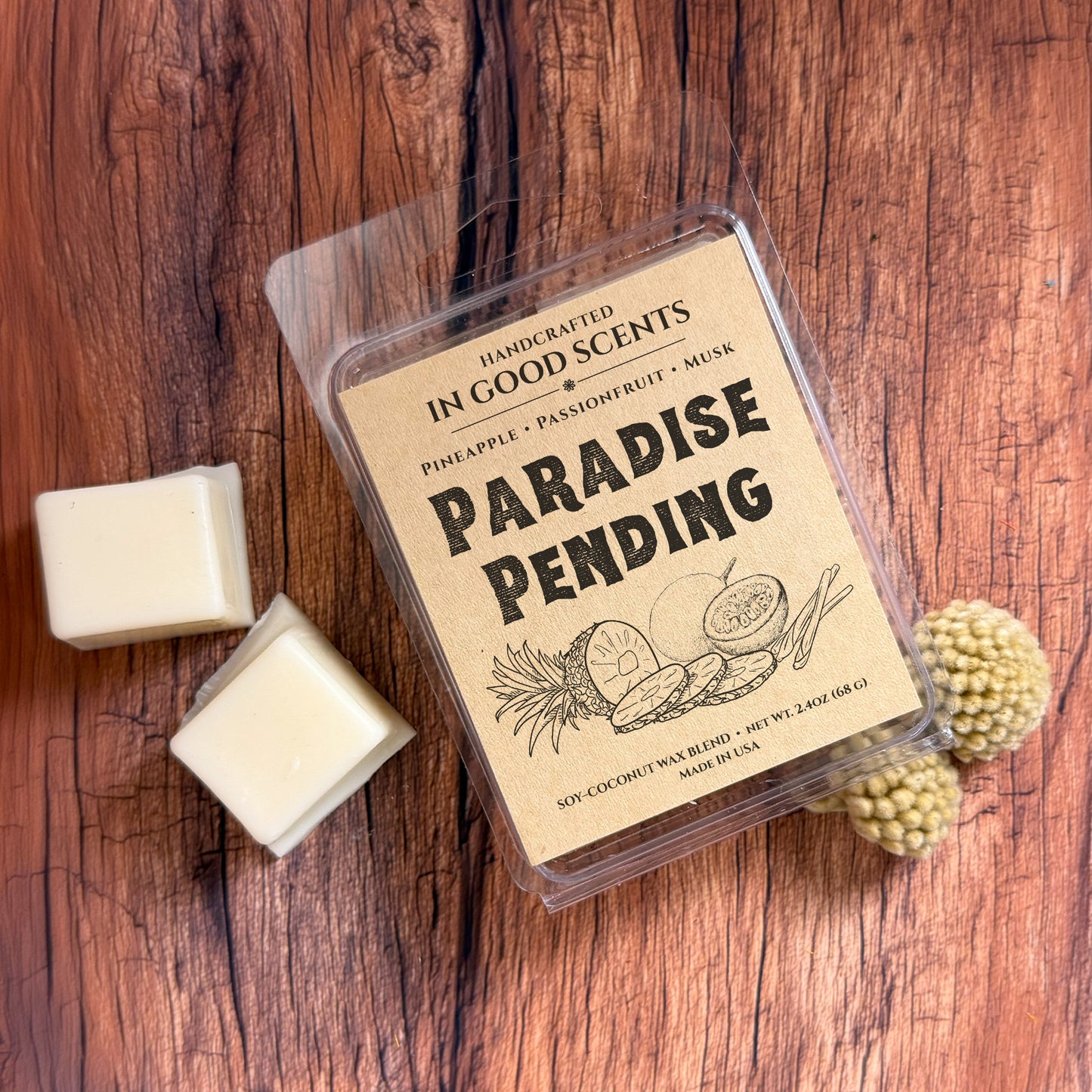 Top-down view of Paradise Pending In Good Scents wax melt clamshell on rustic wood with two wax cubes beside it.