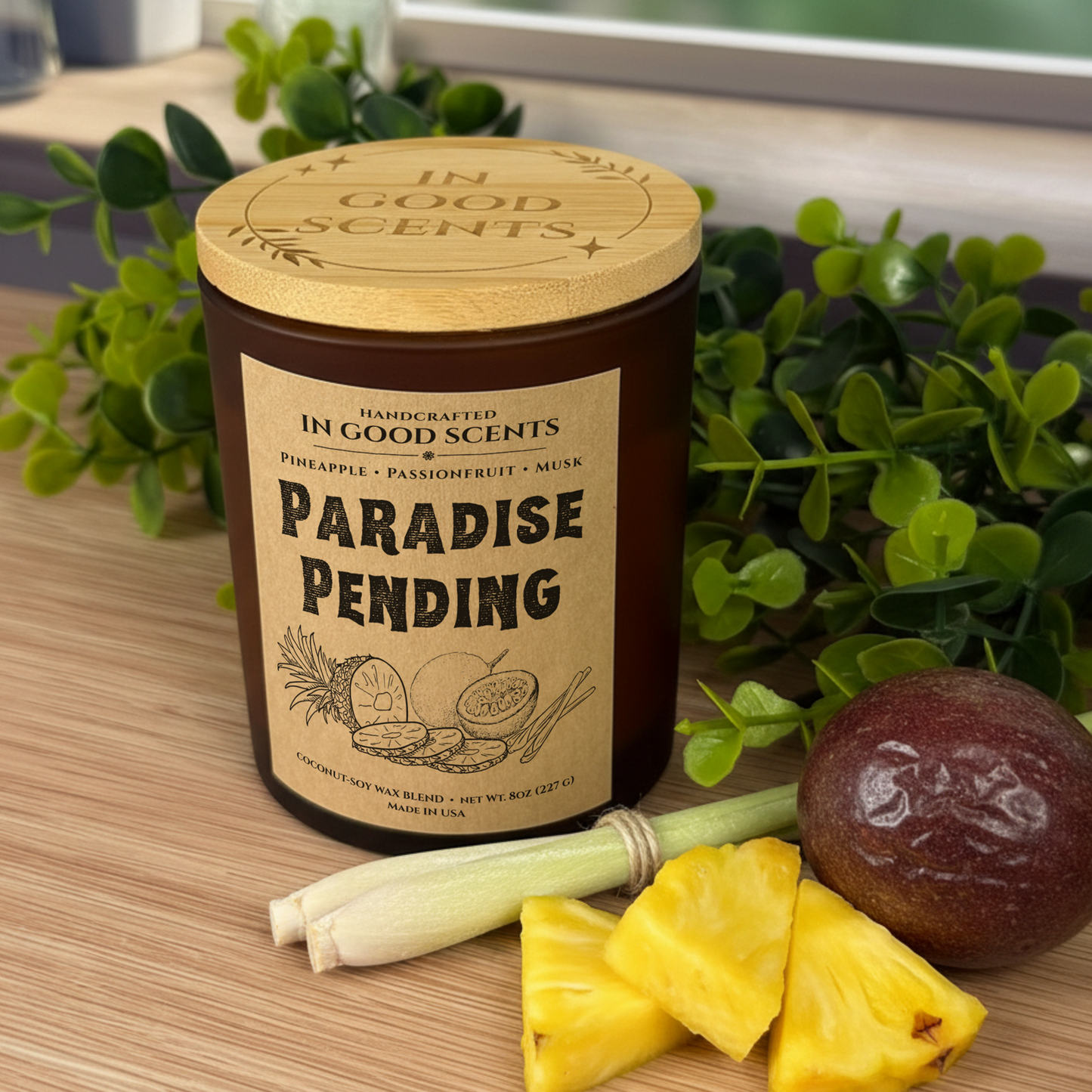 Paradise Pending 8oz coconut-soy candle in amber jar with bamboo lid, styled with pineapple pieces, passionfruit, and greenery.