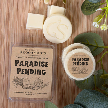 Flat lay of Paradise Pending wax melt clamshell with matching 0.75 oz tart and wax pieces, styled with eucalyptus greenery.