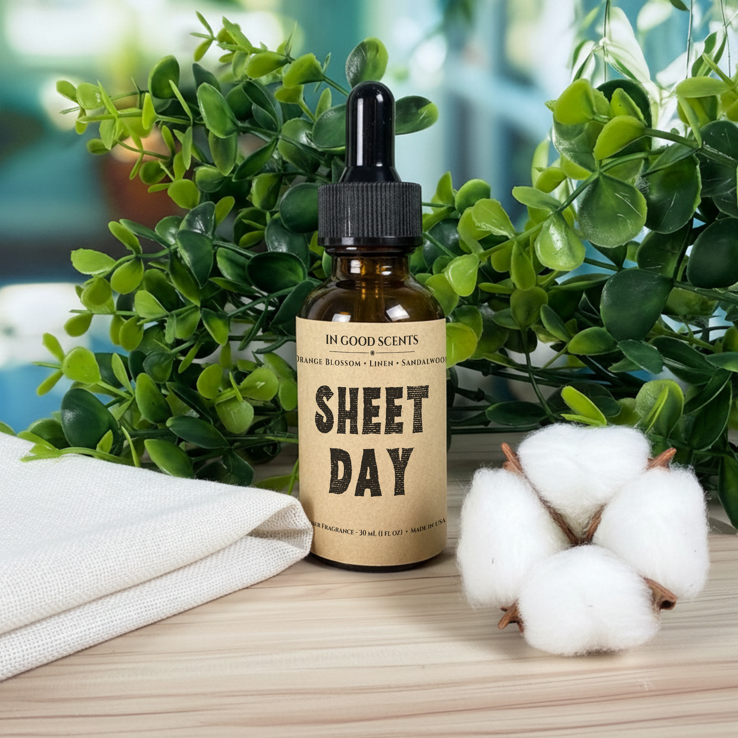 Bottle of 'Sheet Day' product diffuser refill with a dropper on a wooden surface with cotton and greenery in the background.